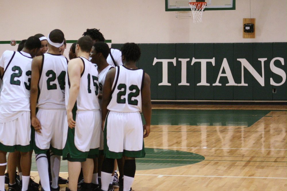 Timber Ridge School's Titan basketball team huddles on the home gym floor during game